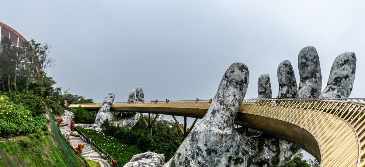 Explore the iconic Golden Bridge in Da Nang, Vietnam, held by giant stone hands amidst lush greenery.