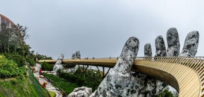 Explore the iconic Golden Bridge in Da Nang, Vietnam, held by giant stone hands amidst lush greenery.